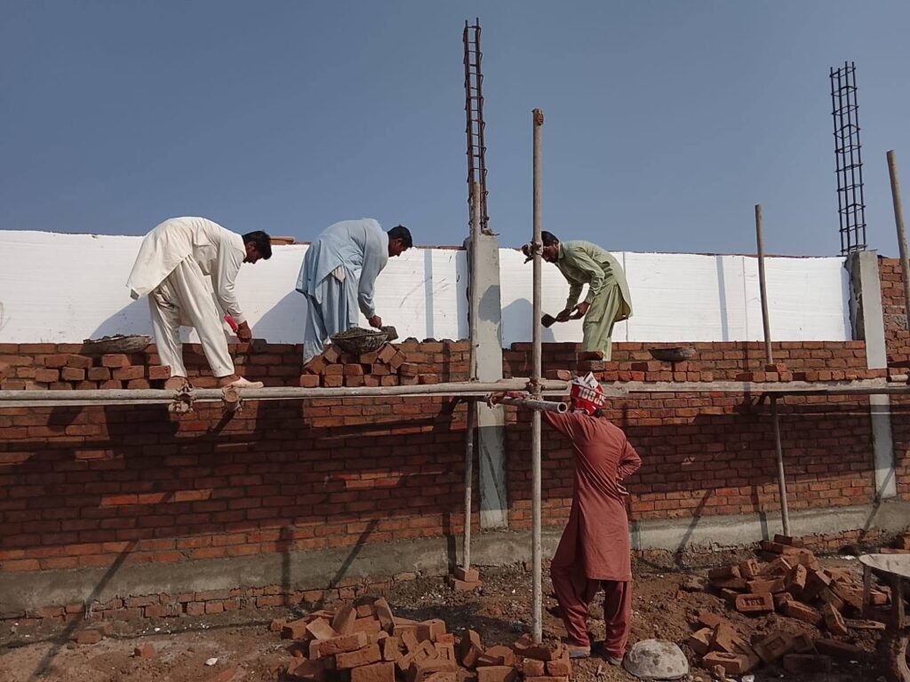Workers unloading thermocol insulation sheets from truck at project site