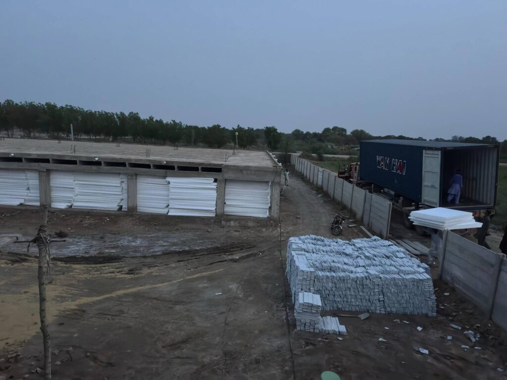 Poultry farm shed with EPS thermocol sheets stacked beside it in Faisalabad - Insulation System